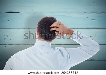 Businessman scratching his head against painted blue wooden planks