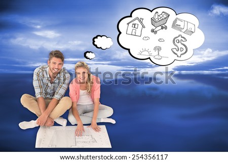 Attractive young couple sitting looking at blueprint against blue sky with blue clouds
