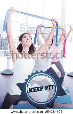 The word keep fit and class holding up exercise belts at yoga class against badge