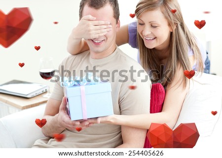 Smiling woman giving a present to her boyfriend against hearts
