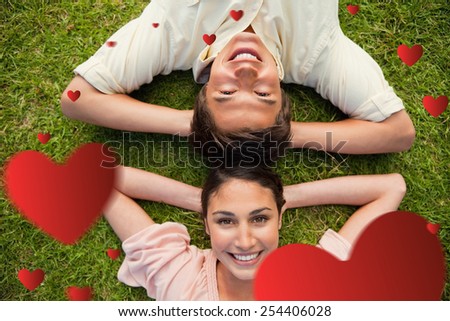 Two friends smiling while lying head to head with both hands behind their neck against hearts