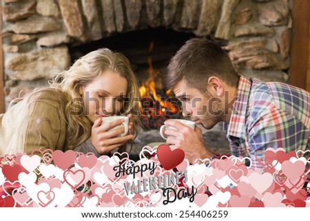 Romantic couple drinking tea in front of lit fireplace against happy valentines day