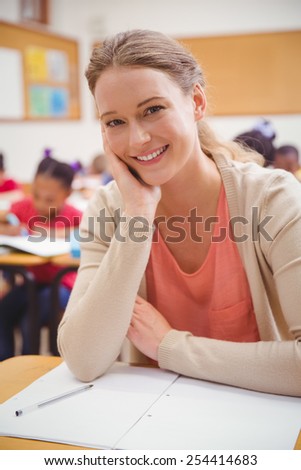 Pretty teacher smiling at camera with head in hand at the elementary school