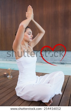 Content brunette in white sitting in lotus pose with hands together against heart