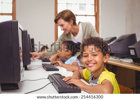 Cute pupils in computer class smiling at camera at the elementary school