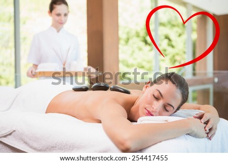 Beautiful woman receiving stone massage at health farm against heart