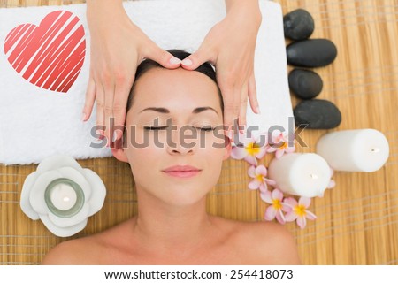 Smiling brunette enjoying a head massage against red heart