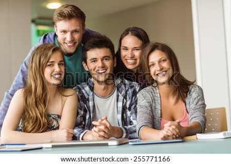 Portrait of smiling friends posing near their laptop at school