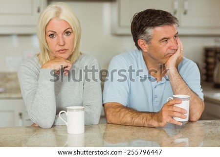 Mature couple having coffee together not talking at home in the kitchen