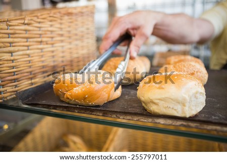 Hand of server taking bread with tongs at the bakery