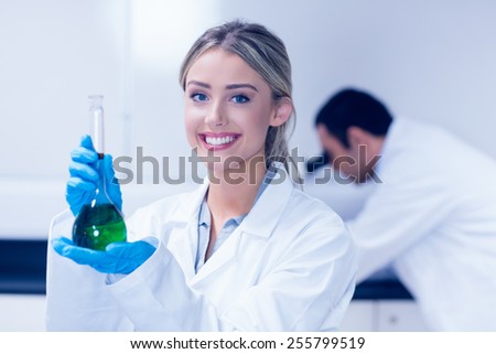 Science student holding green chemical in beaker at the university