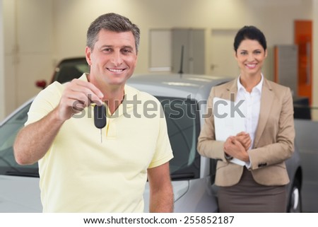 Smiling customer showing his new car key at new car showroom