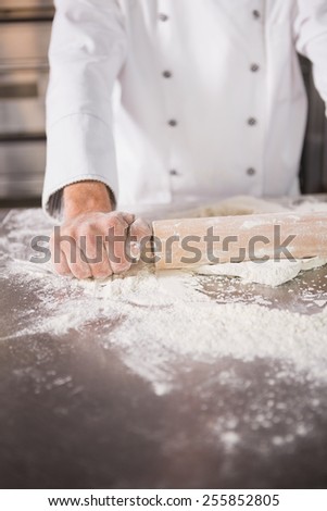 Close up of baker using a rolling pin in the kitchen of the bakery
