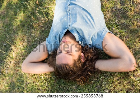 Young man lying down in the park on a summers day