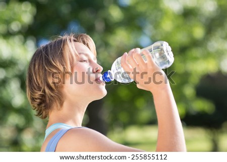 Fit blonde in the park drinking water on a sunny day