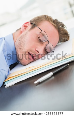 Tired businessman with stack of files on desk in his office