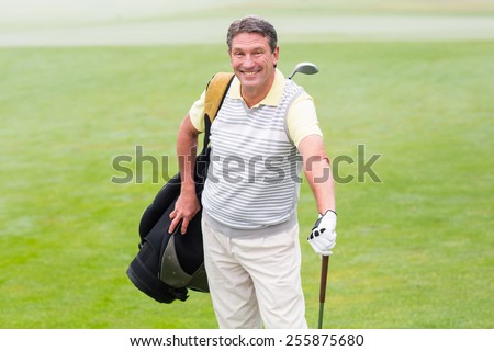 Handsome golfer standing with golf bag on a foggy day at the golf course