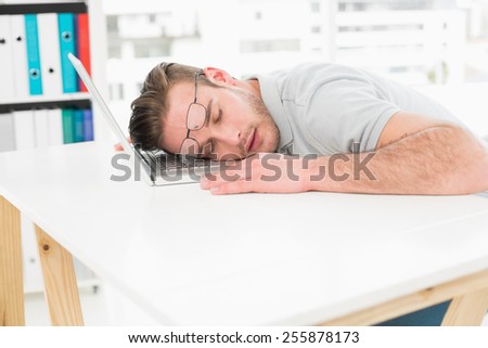 Tired businessman resting on laptop in his office