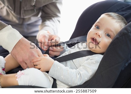 Parents securing baby in the car seat in his car