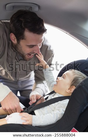 Father securing baby in the car seat in his car