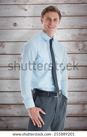 Smiling businessman standing with hand in pocket against wooden planks