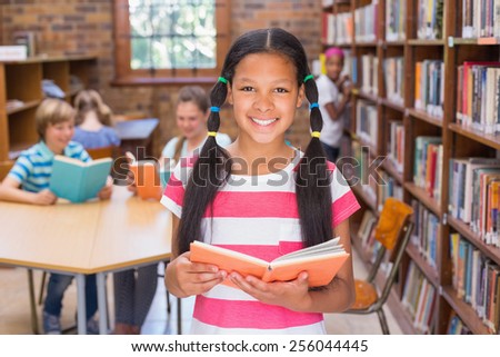 Cute pupil looking for books in library at the elementary school