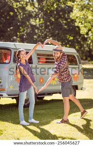 Hipster couple making heart with arms on a summers day