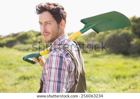 Happy farmer carrying his shovel on a sunny day