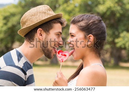 Cute couple sharing a lollipop on a sunny day