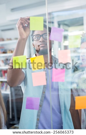 Creative young businessman writing on adhesive note in office