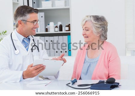 Happy male doctor explaining prescriptions to senior patient in clinic