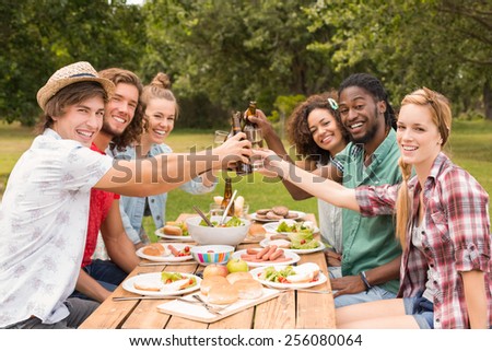Happy friends in the park having lunch on a sunny day