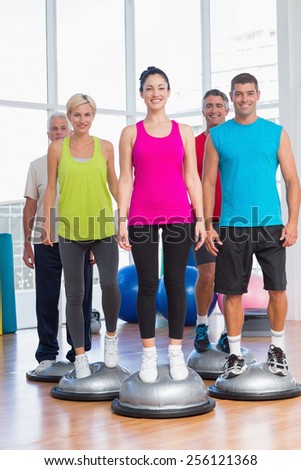 Full length portrait of people standing on balance balls in gym