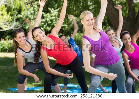 Fitness group doing yoga in park on a sunny day
