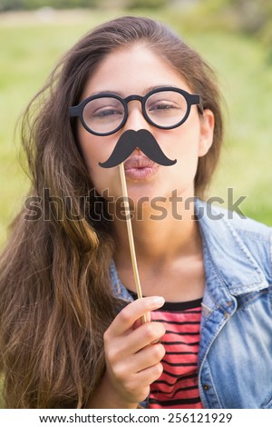 Pretty brunette with fake mustache on a sunny day