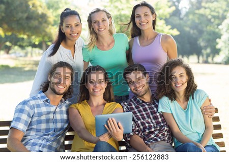 Smiling friends in the park using tablet pc on a sunny day
