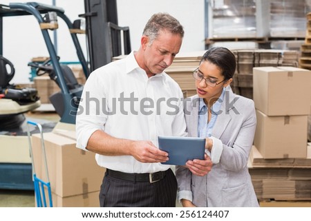 Warehouse manager and her boss working together in a large warehouse