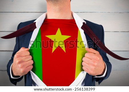 Businessman opening shirt to reveal cameroon flag against painted blue wooden planks