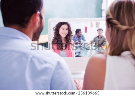 Colleagues looking at computer against smiling woman with creative team working behind