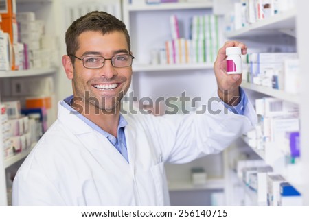 Handsome pharmacist holding medicine jar at the hospital pharmacy