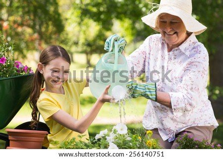 Happy grandmother with her granddaughter gardening on a sunny day