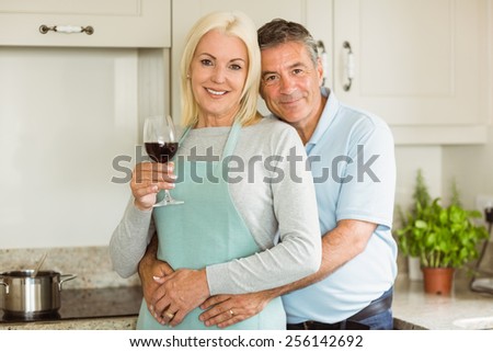 Happy mature couple smiling at camera at home in the kitchen