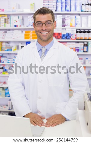 Handsome pharmacist using the computer at the hospital pharmacy
