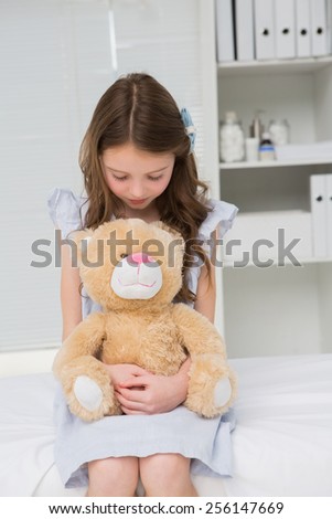 Little girl with her teddy bear in her harms in medical office