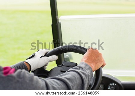 Golfer driving his golf buggy forward on a sunny day at the golf course