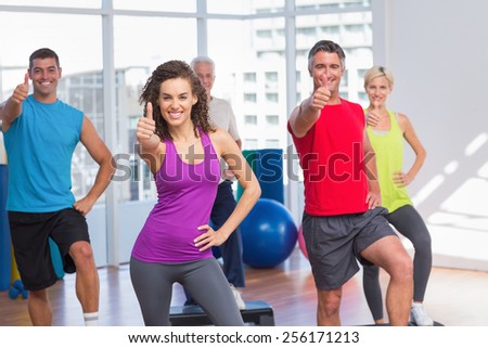 Portrait of fit people gesturing thumbs up in fitness class