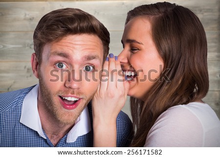 woman whispering secret into friends ear against bleached wooden planks background