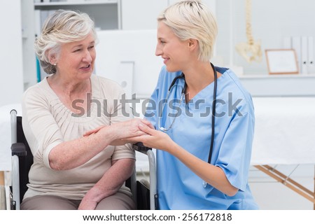 Smiling female nurse checking flexibility of patients wrist in clinic
