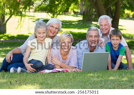 Happy family using laptop in the park on a sunny day