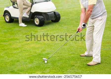 Golfer about to tee off with partner behind him on a foggy day at the golf course